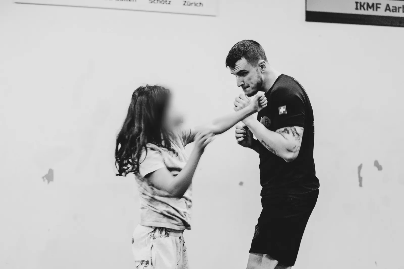 Instruktor übt mit einem Kind eine Abwehrtechnik im Training